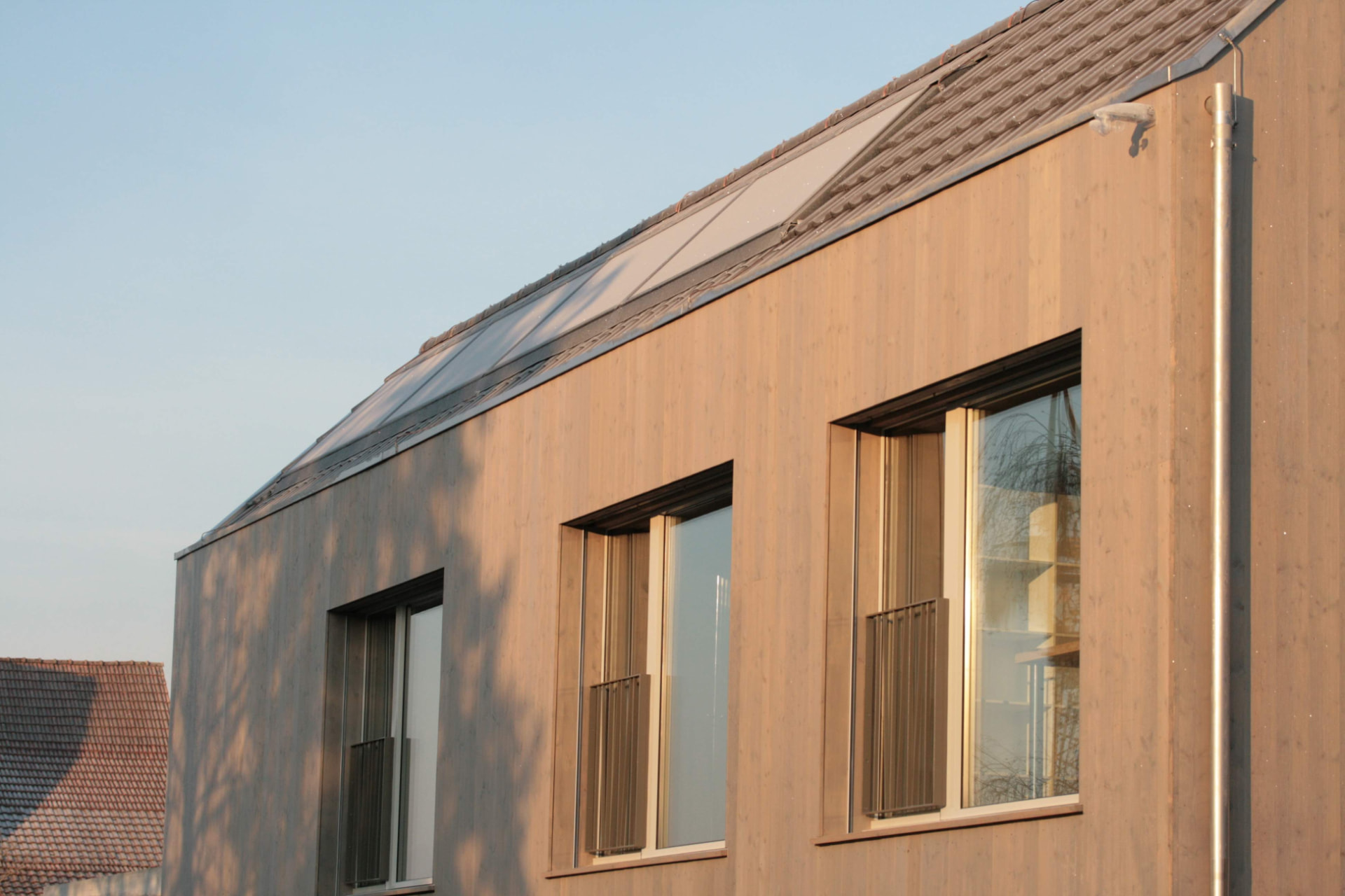 Obergeschoss eines Wohnhauses mit Holzfassade im Abendlicht